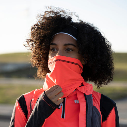 A woman with a bright fluorescent coral cowl covering her nose and mouth.